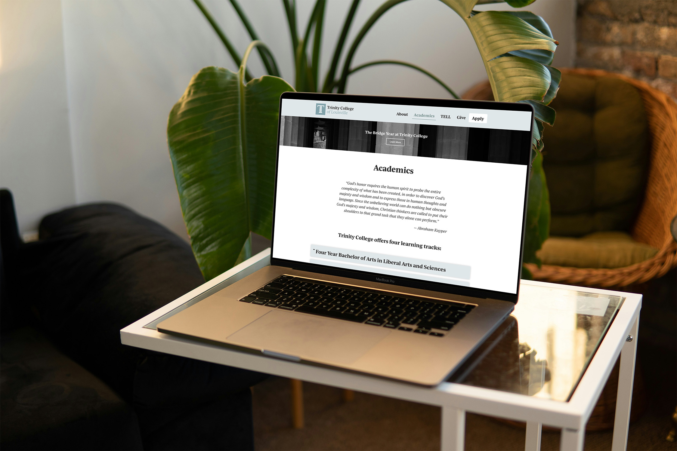 Trinity college website displayed on MacBook sitting on a coffee table